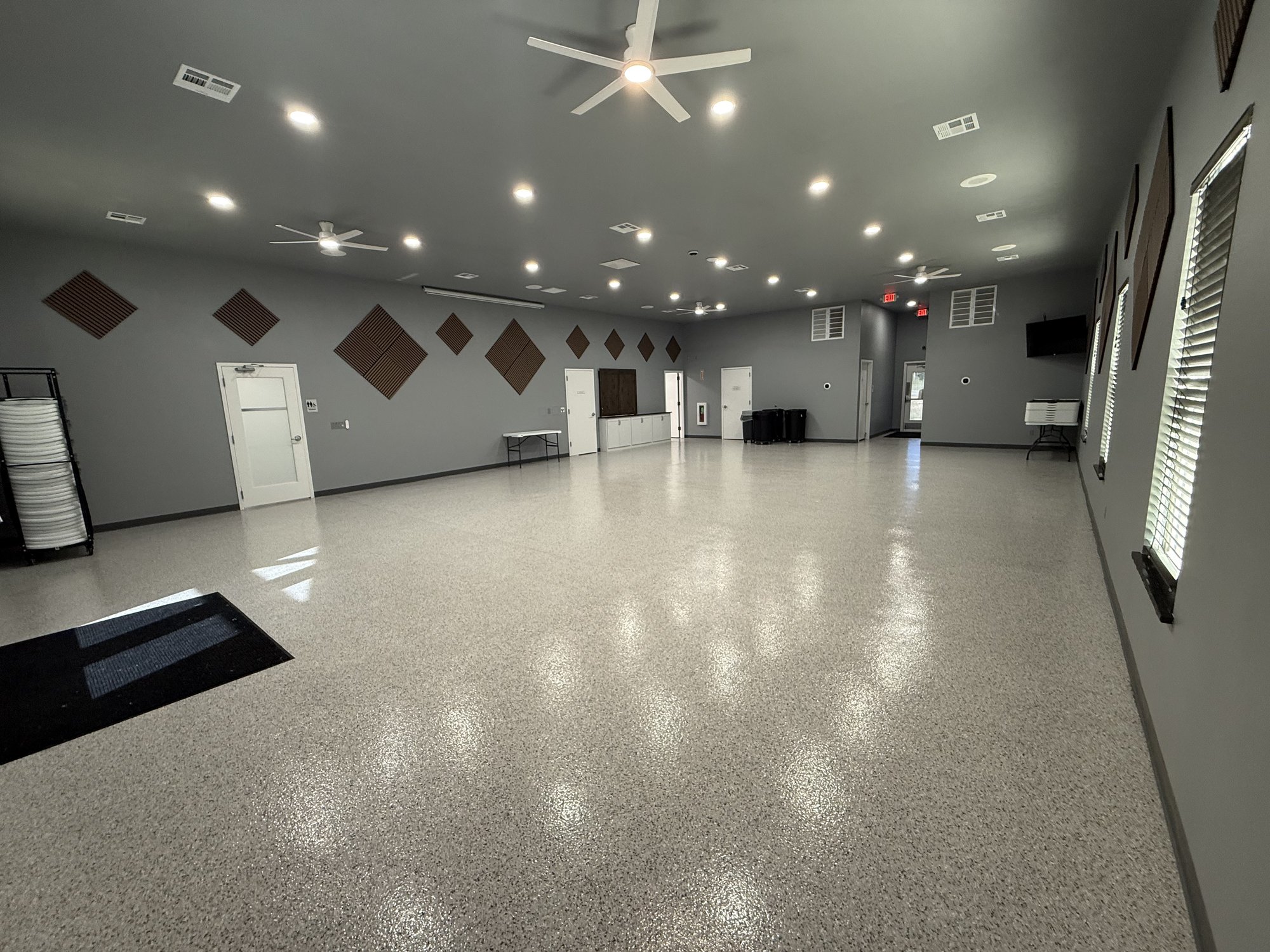 Open main hall of the Talala Community Center with ceiling fans and speckled floor