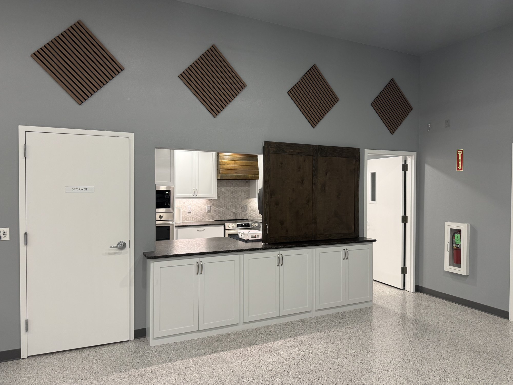 Kitchen pass-through with white cabinets and dark counter in the Community Center