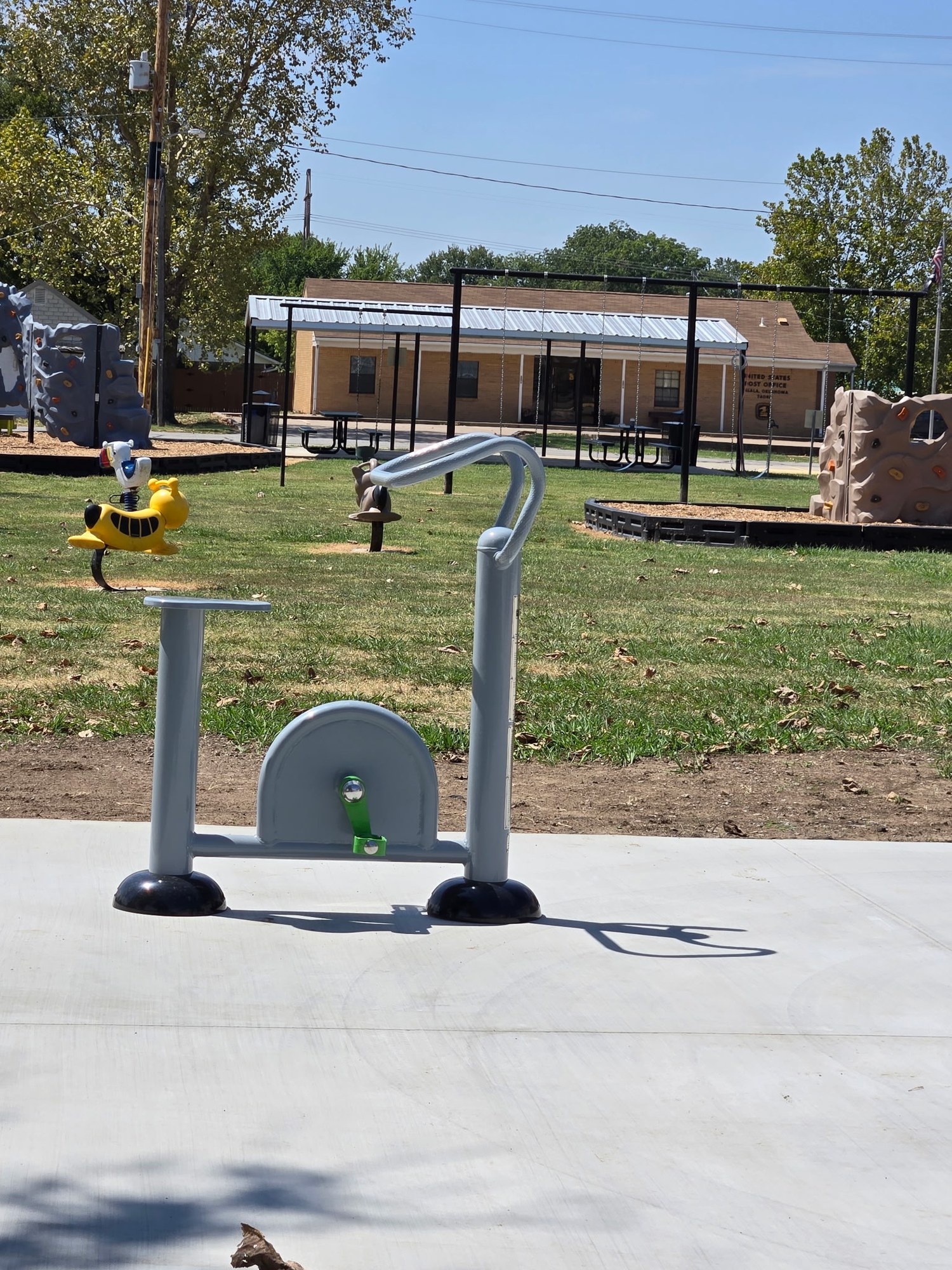 Outdoor fitness bike at Town Park with playground beyond